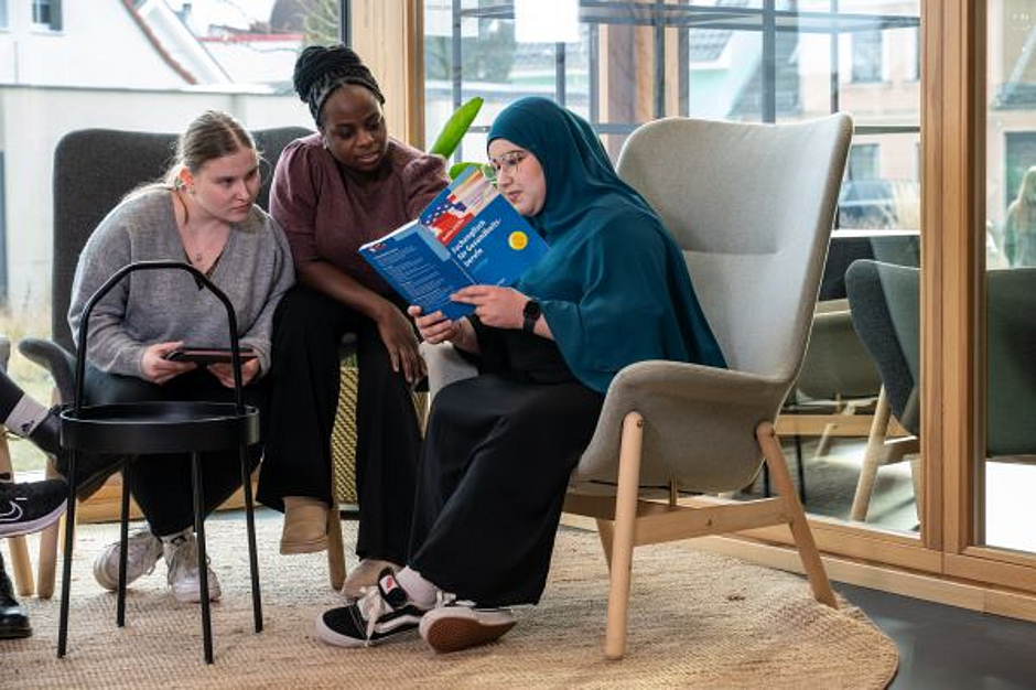 Drei Auszubildende schauen gemeinsam in ein Buch