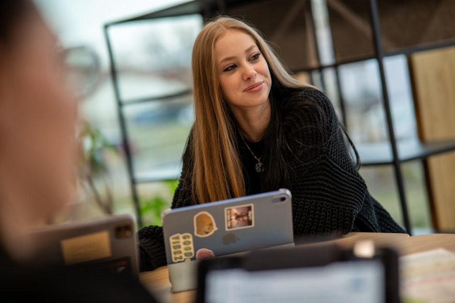Auszubildende schaut strahlend vom Tablet auf