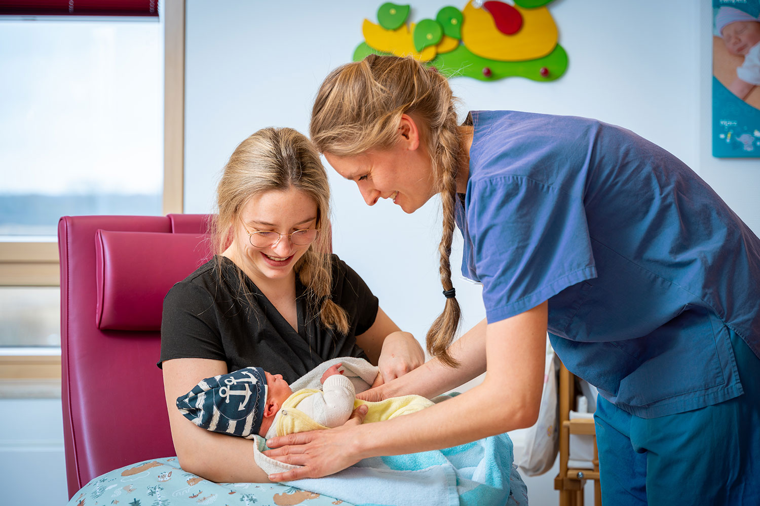 Neugeborenes mit Mama daneben Hebamme
